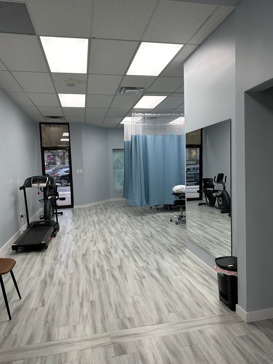 The clinic corridor, with cardio equipment, a curtained treatment bay and a full-length mirror
