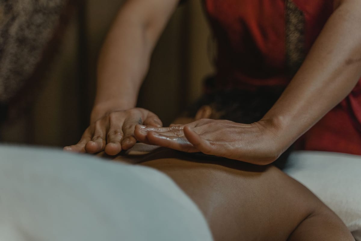 A massage therapist working on a draped client's back